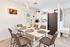 A modern kitchen with white cabinets, a black refrigerator, and a dining area with a white table and six chairs. - Picture Your Stay | Beautifully renovated home (San Antonio)