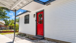 A single-story house with a red door, white siding, and a covered porch. - Picture Your Stay | Beautifully renovated home (San Antonio)