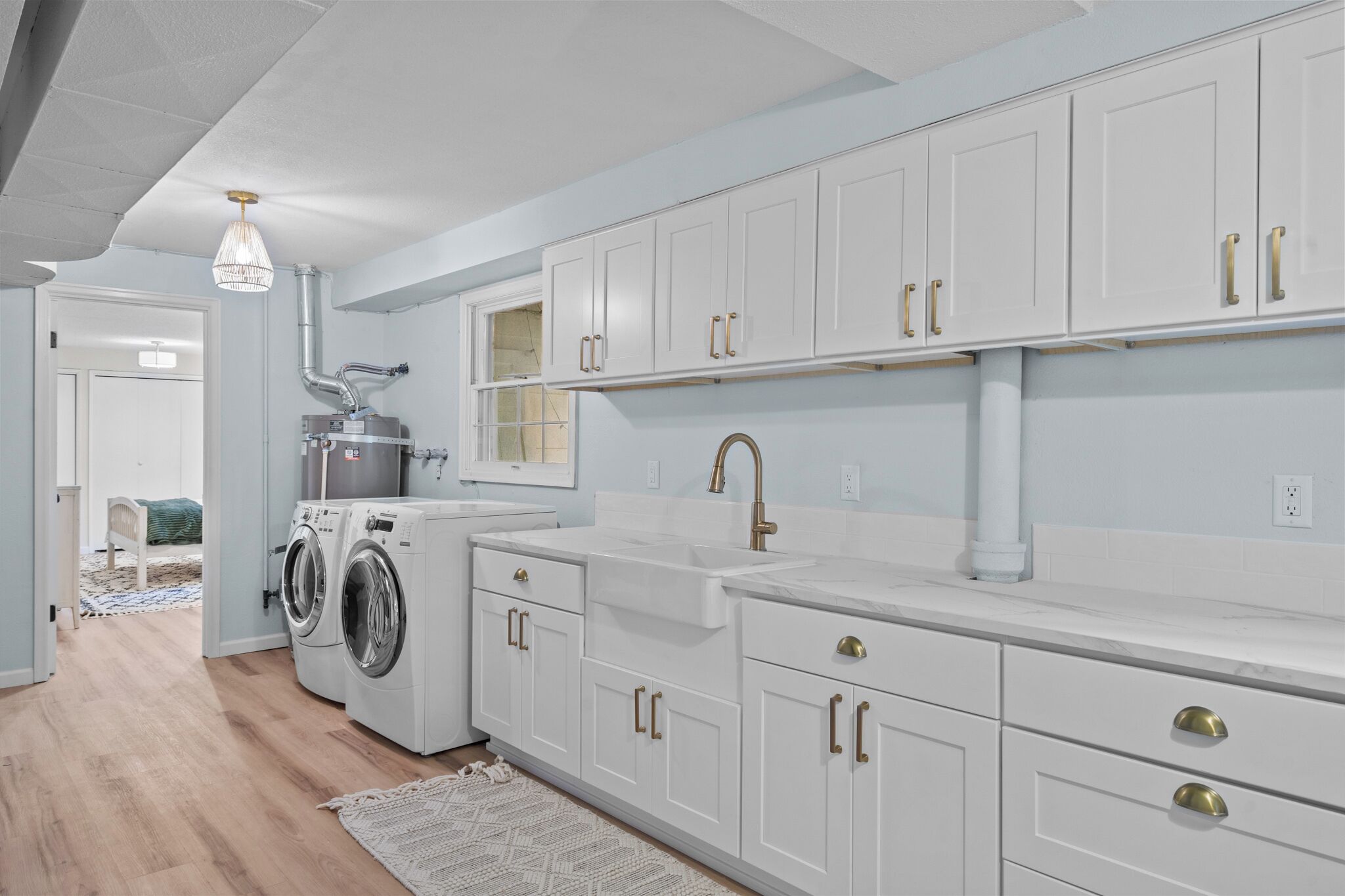A modern kitchen with white cabinets, gold handles, and a built-in washing machine.