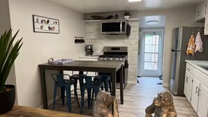 A modern kitchen with a central island, bar stools, a stove, microwave, and a refrigerator. - Remodeled home across from river, train and park! (Cañon City)