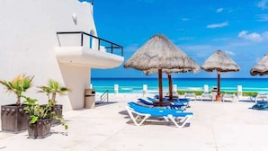Un complejo turístico con piscina, sillones reclinables y sombrillas de paja.