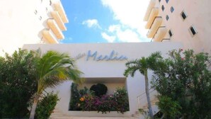 Entrada de hotel con un letrero que dice 'Marlin', rodeada de follaje y un cielo despejado.