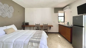 Un dormitorio con cama, escritorio, refrigerador y televisor.