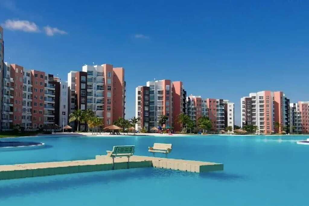 A resort with a large swimming pool, high-rise buildings, and palm trees.