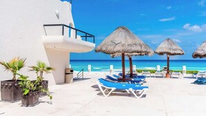 Ein Resort mit Poolbereich, Liegestühlen und Reetdachschirmen.