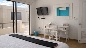 Ein Hotelzimmer mit einem Bett, einem Schreibtisch, einem Stuhl, einem Fernseher und einem Fenster.