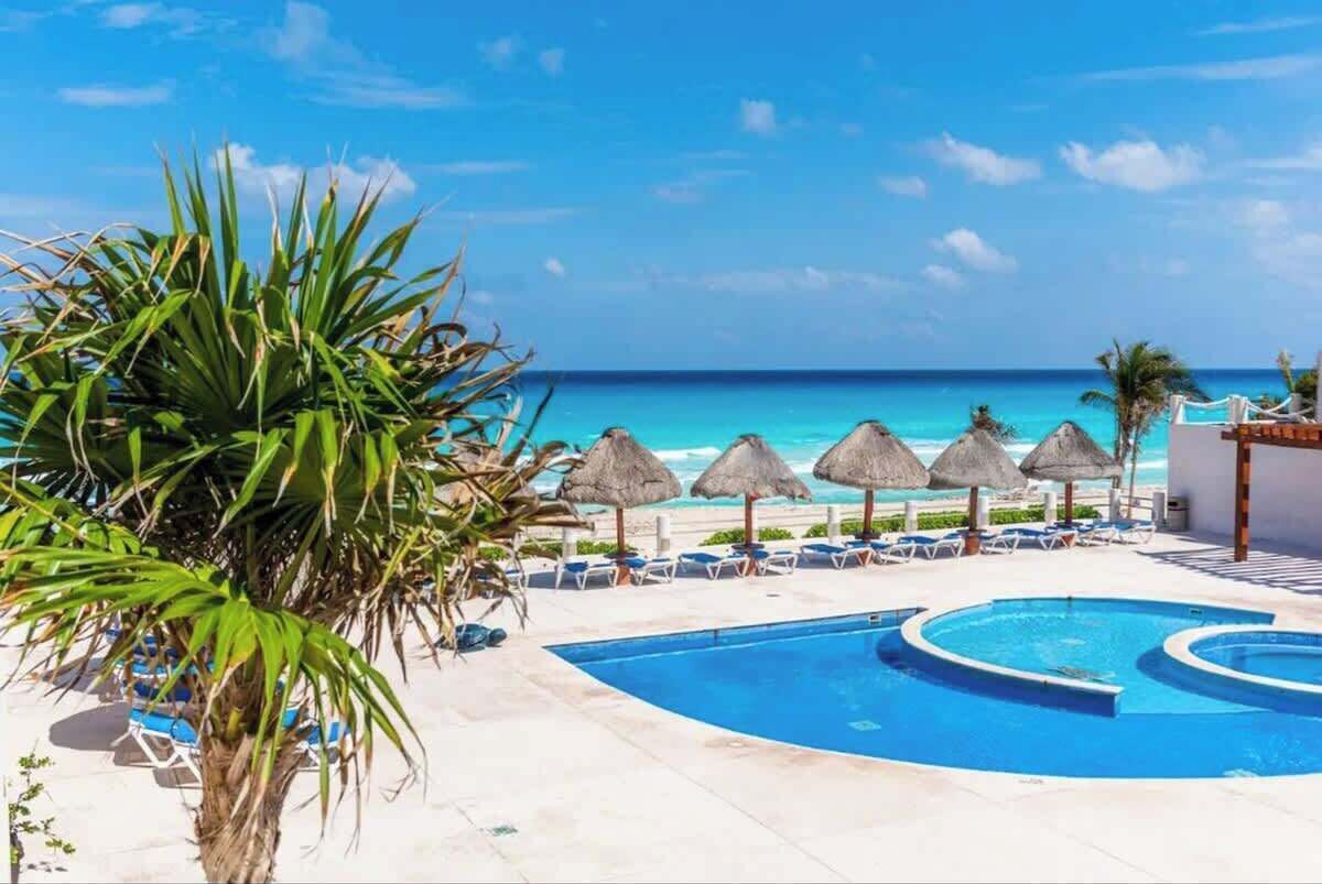 A pool area with lounge chairs and umbrellas, overlooking a beach.