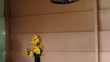 Una pared con un letrero que dice "Costa Rica Pura Vida" y un jarrón con flores amarillas sobre una estantería.