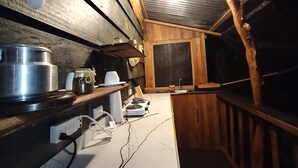 Une cuisine de taille réduite, dotée d’étagères en bois, d’un évier et d’une cuisinière.