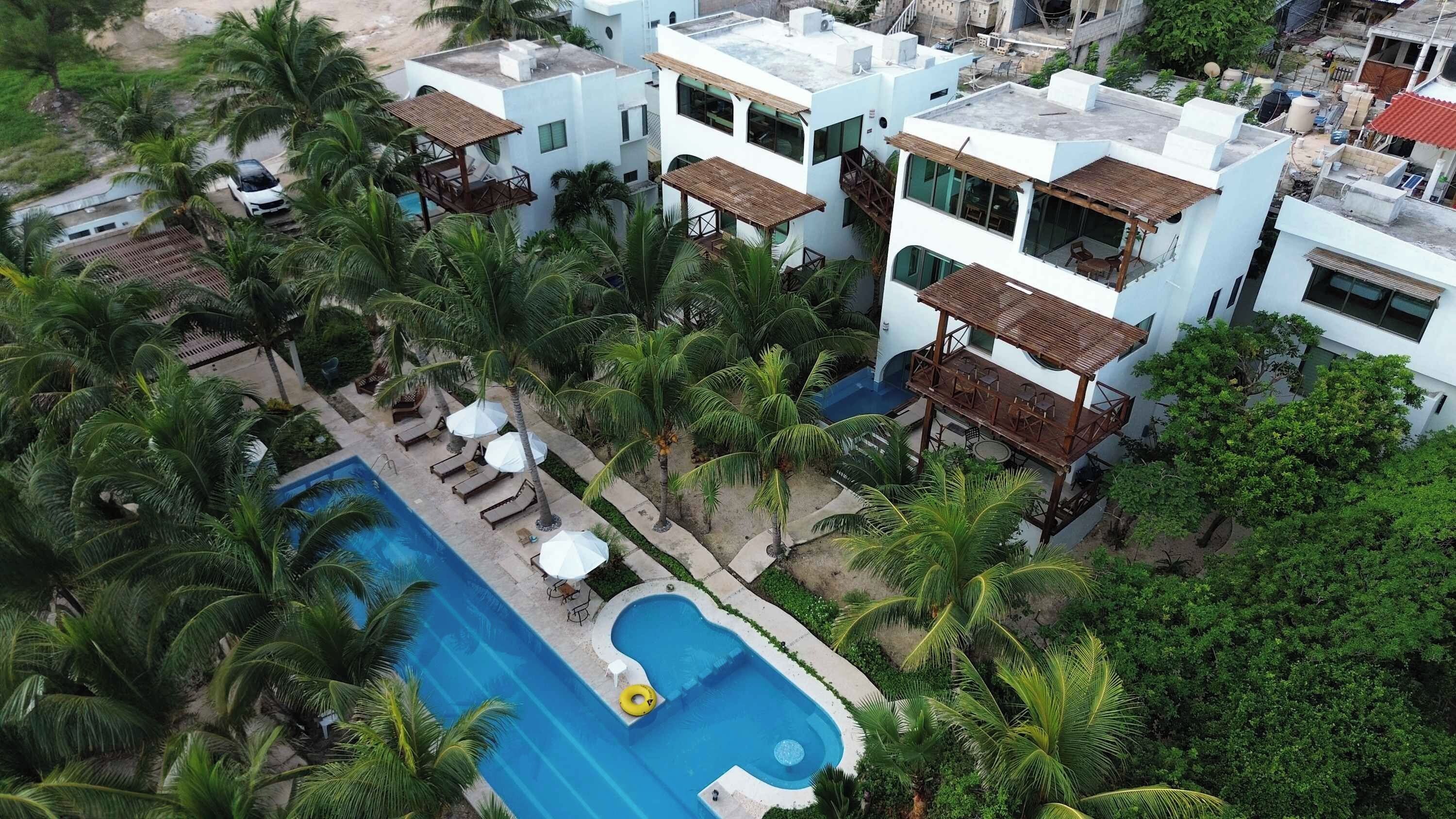 Ein Resort mit Schwimmbad, mehreren Gebäuden und Palmen.