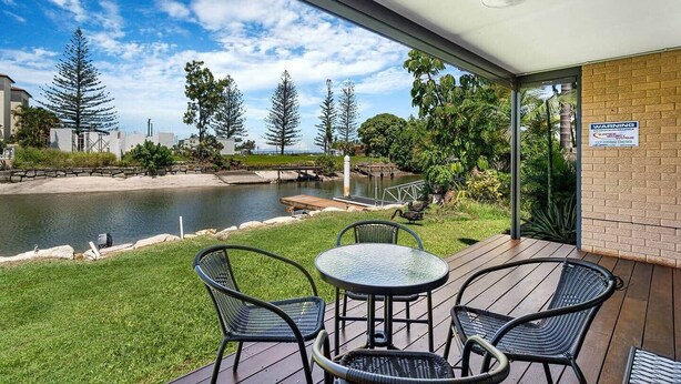 A patio with a view of a river, surrounded by greenery and trees. - Canal Luxury living & boat ramp (Runaway Bay)