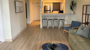 A modern kitchen with a built-in oven, a ceiling fan, and a bar area with stools. - 2-bedroom apartment in Waikiki with PARKING included (Honolulu)