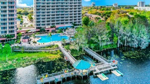 A hotel with a pool area, a dock, and a view of the surrounding landscape. - Lakefront condo with amazing views, pool, & hot tub - steps from the beach (Orlando)