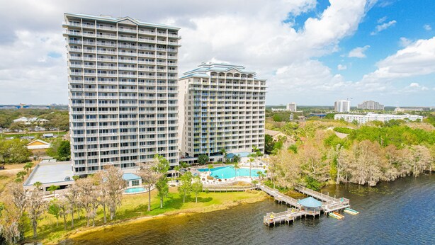 A high-rise hotel with a swimming pool and dock. - Lakefront condo with amazing views, pool, & hot tub - steps from the beach (Orlando)