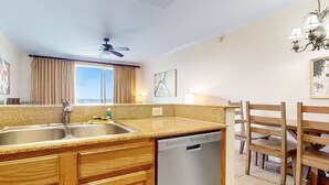 A kitchen with granite countertops, wooden cabinets, a dishwasher, and a dining area with wooden chairs and a table. - Lakefront condo with amazing views, pool, & hot tub - steps from the beach (Orlando)