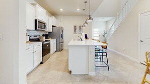 A modern kitchen with white cabinetry, stainless steel appliances, and a central island. - Amazing home with outdoor patio, wifi, & close to local attractions near Orlando (Clermont)