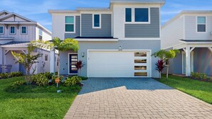 A modern two-story house with a garage, surrounded by well-maintained lawns and small trees. - Amazing home with outdoor patio, wifi, & close to local attractions near Orlando (Clermont)
