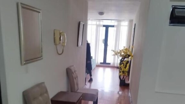 A spacious living room with a wooden floor, a beige sofa, a small table, and a potted plant. - Flor y Canto  (Matehuala)