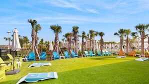 A poolside area with artificial grass, lounge chairs, and palm trees. - Contemporary townhouse w/ private pool and resort amenities, near attractions (Clermont)