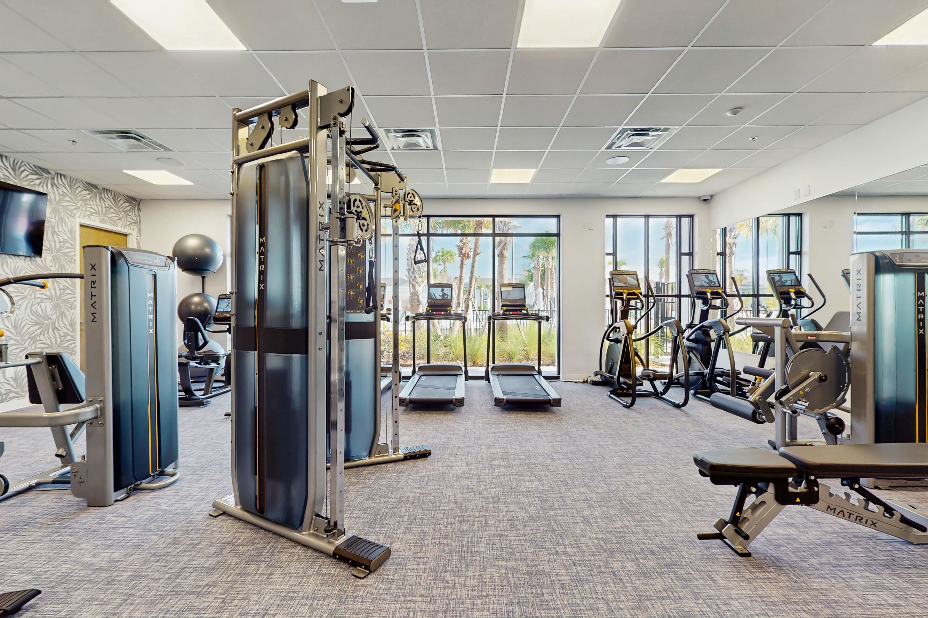 Une salle de sport équipée de machines de cardio, de matériel de musculation et de tapis de course.