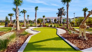 A landscaped area with a winding path, palm trees, and a giraffe statue. - Contemporary townhouse w/ private pool and resort amenities, near attractions (Clermont)