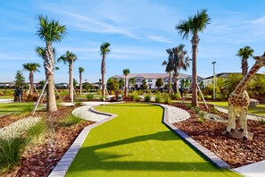 A landscaped area with a winding path, palm trees, and a giraffe statue. - Contemporary townhouse w/ private pool and resort amenities, near attractions (Clermont)