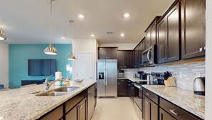 A modern kitchen with granite countertops, stainless steel appliances, and dark wooden cabinets. - Contemporary townhouse w/ private pool and resort amenities, near attractions (Clermont)