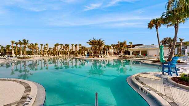 A swimming pool with a clear blue water, surrounded by palm trees and lounge chairs. - Contemporary townhouse w/ private pool and resort amenities, near attractions (Clermont)