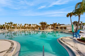 A swimming pool with a clear blue water, surrounded by palm trees and lounge chairs. - Contemporary townhouse w/ private pool and resort amenities, near attractions (Clermont)