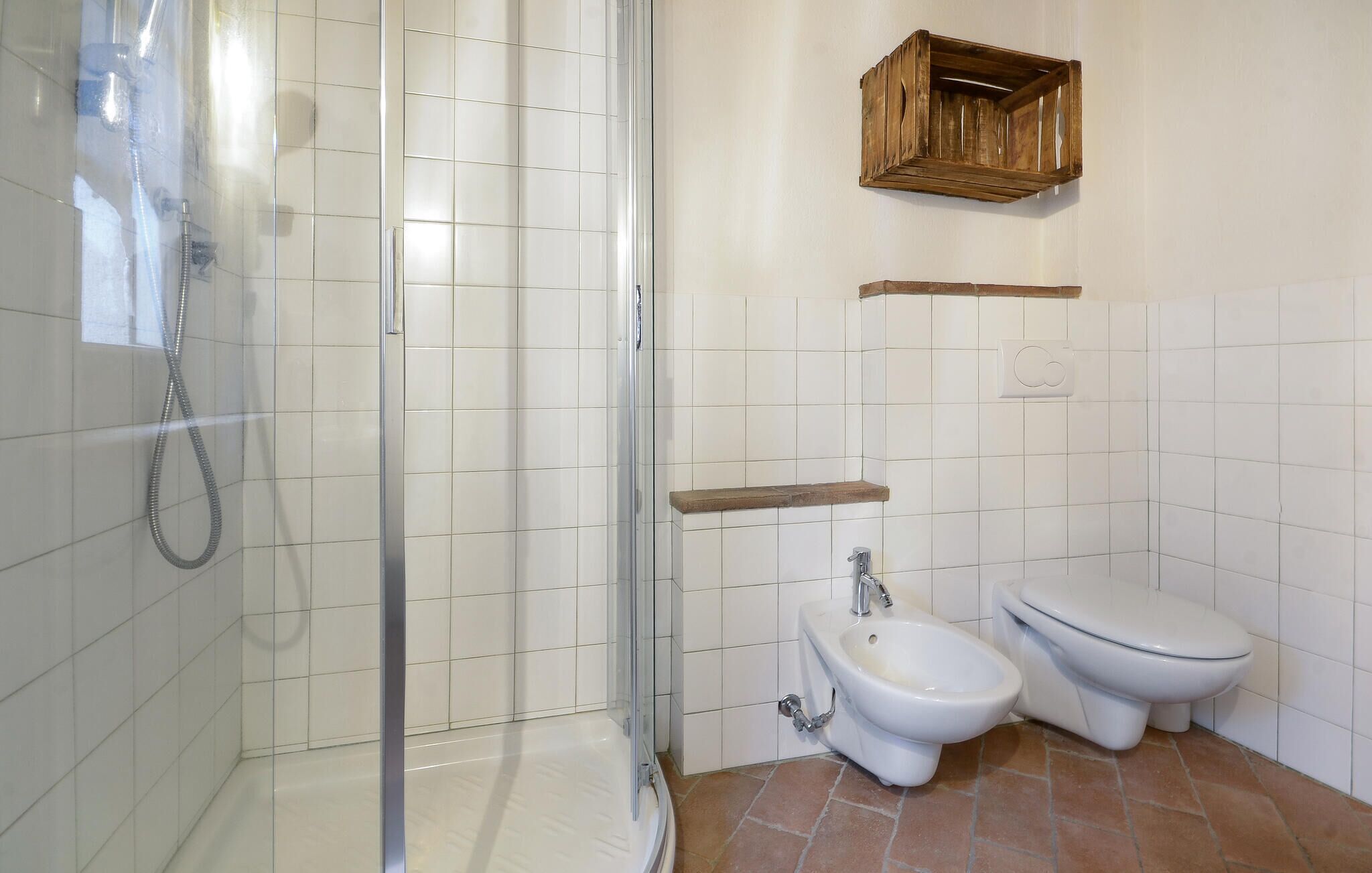 A bathroom with a glass-enclosed shower, a toilet, and a bidet.