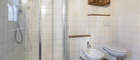 A bathroom with a glass-enclosed shower, a toilet, and a bidet.