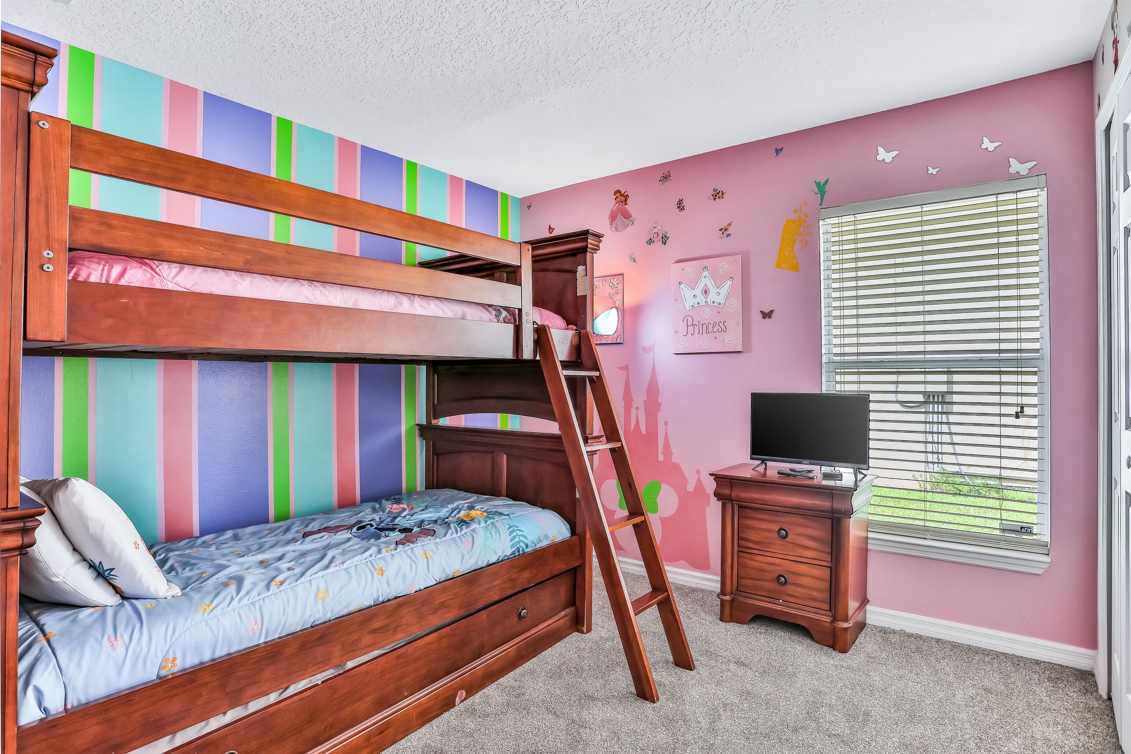 A bunk bed with a wooden ladder, a dresser, and a window with blinds.