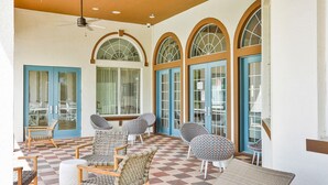 A covered patio area with wicker furniture, a checkered floor, and large arched windows with blue doors. - Dog-friendly home with private outdoor pool, high-speed WiFi, and central AC (Davenport)