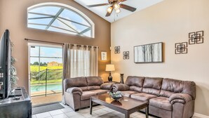 A living room with a sectional sofa, a coffee table, a ceiling fan, and a large window with curtains. - Dog-friendly home with private outdoor pool, high-speed WiFi, and central AC (Davenport)