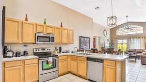A modern kitchen with wooden cabinets, stainless steel appliances, and a large island. - Dog-friendly home with private outdoor pool, high-speed WiFi, and central AC (Davenport)