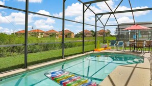 A swimming pool with a glass enclosure, surrounded by a patio area with chairs and an umbrella. - Dog-friendly home with private outdoor pool, high-speed WiFi, and central AC (Davenport)