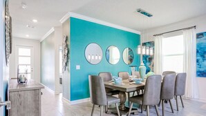 Un comedor con una pared azul turquesa, espejos redondos y una araña.