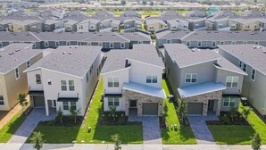 Zona residencial con casas modernas que tienen techos planos, ventanas amplias y un camino de acceso central.