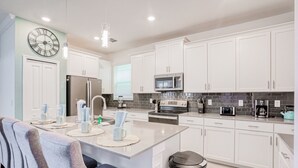 Una cocina moderna con armarios blancos, electrodomésticos de acero inoxidable y una isla central con asientos.