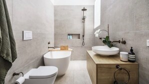 Une salle de bain moderne avec une baignoire sur pieds, des toilettes et un lavabo avec un meuble-vasque en bois.