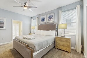 Ein Schlafzimmer mit Bett, Nachttischen, Deckenventilator und Bildern an den Wänden.