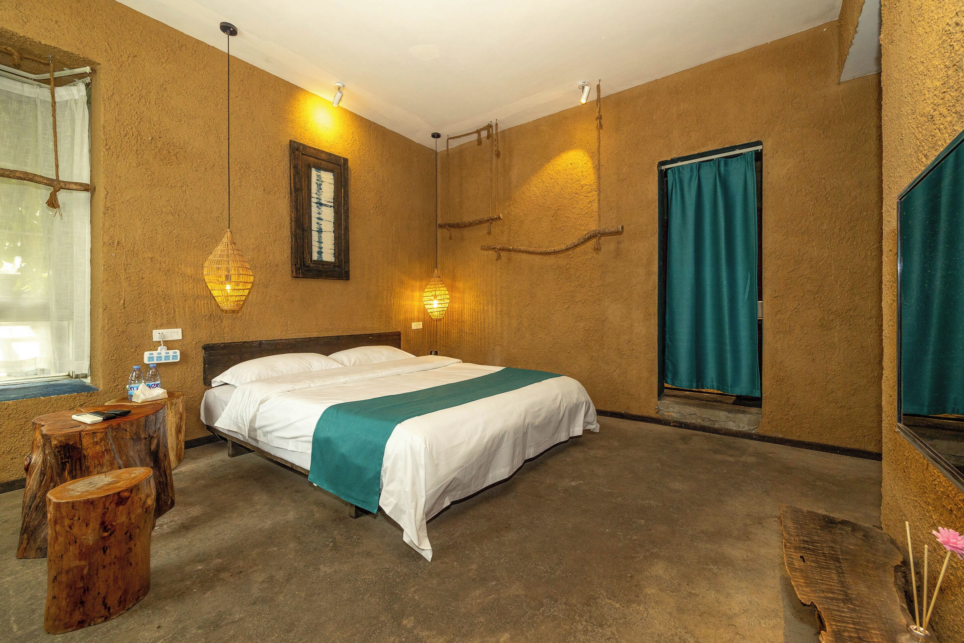 Un dormitorio con cama, mesita de noche, ventana con cortinas e iluminación en la pared.