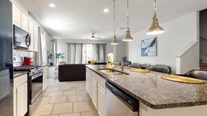 A modern kitchen with granite countertops, stainless steel appliances, and pendant lighting. - Modern retreat with private pool, lanai, central AC & gas grill (Davenport)