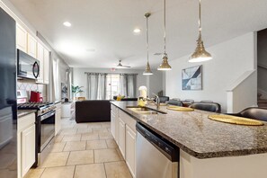 Eine moderne Küche mit Granit-Arbeitsplatten, Edelstahlgeräten und Pendelleuchten.
