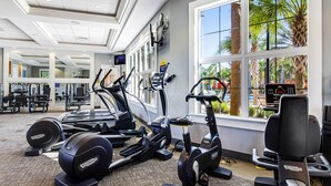 A gym with treadmills, elliptical machines, and weight machines, large windows with a view of palm trees, and a ceiling with recessed lighting. - Modern retreat with private pool, lanai, central AC & gas grill (Davenport)