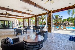 Eine Außenpatio-Terrasse mit runden Tischen, Stühlen und einem Pool.