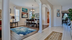 A spacious living area with a dining table, chairs, and a blue patterned rug. - Stunning house with lanai, pool, ping-pong, full kitchen, & WiFi (Davenport)