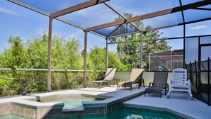 A glass-enclosed swimming pool with lounge chairs and a hot tub, surrounded by greenery. - Stunning house with lanai, pool, ping-pong, full kitchen, & WiFi (Davenport)