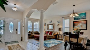 A spacious living area with a dining table, sofas, and a large window. - Stunning house with lanai, pool, ping-pong, full kitchen, & WiFi (Davenport)