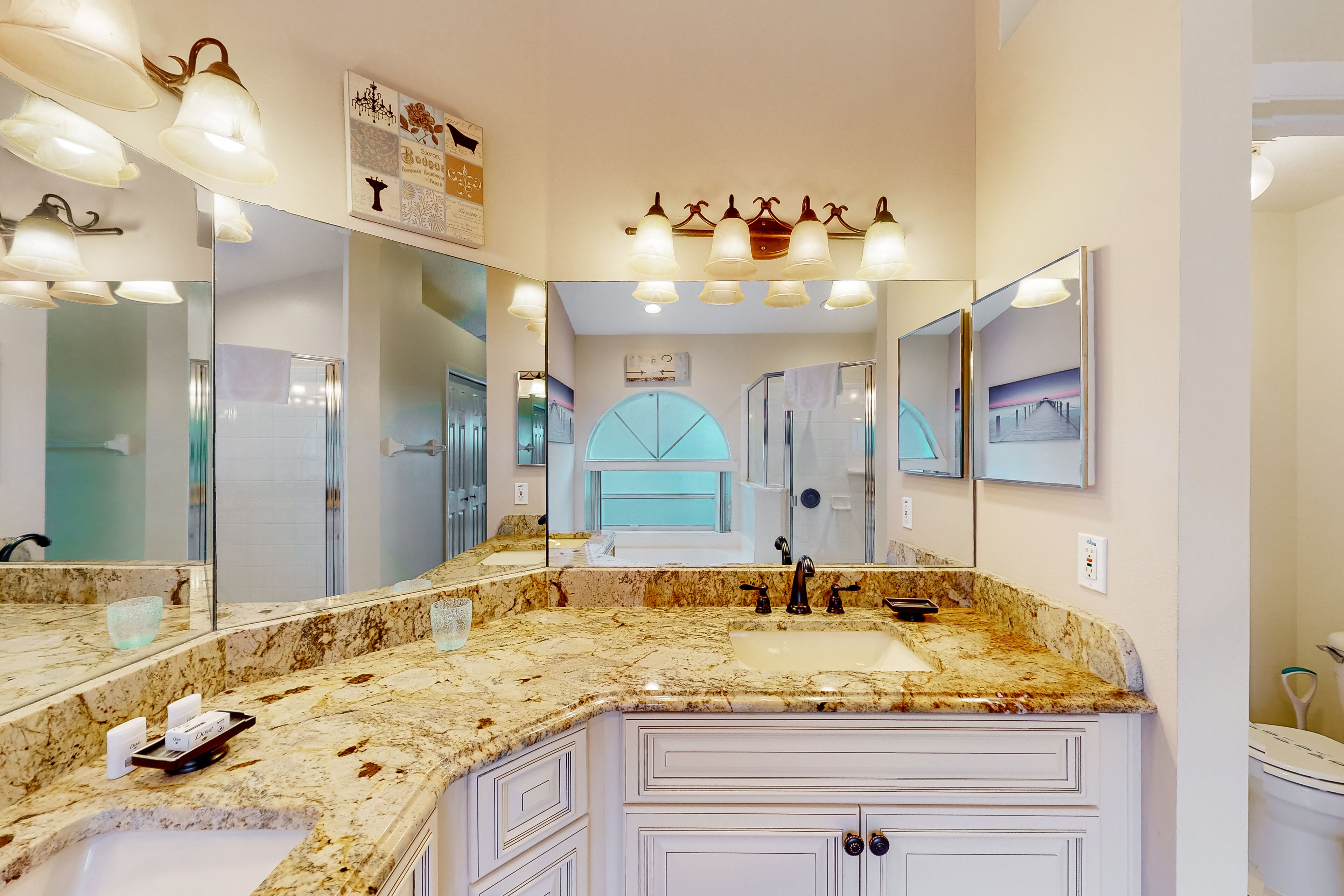 A bathroom with a large vanity, multiple mirrors, and a marble countertop.